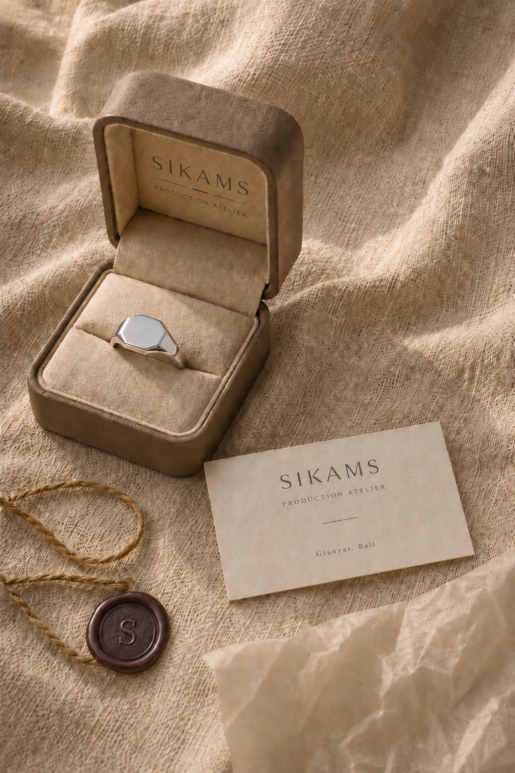 Jeweler's hands filing a silver signet at the bench